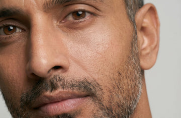 Close-up of a man's face with a neutral expression on a gray background
